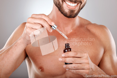 Image of Hand, product and serum with a man model in studio on a gray background holding a glass bottle. Beauty, skincare and antiaging with a male inside to apply oil to his body for natural treatment