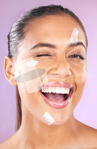 Image of Woman face, skincare and beauty cream wink for dermatology, health and wellness of natural glow skin on purple background. Portrait of aesthetic cosmetic model in studio with secret sunscreen product