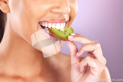 Image of Woman, face and kiwi for skincare beauty wellness, natural cosmetic health and fruit nutrition diet in purple studio background. Model eating, vitamin c and facial smile for organic skin or body glow
