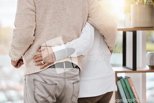 Image of Love, hug and senior couple in their home standing, bonding and spending quality time together. Care, support and elderly woman in retirement holding husband while watching the sunset at their house.