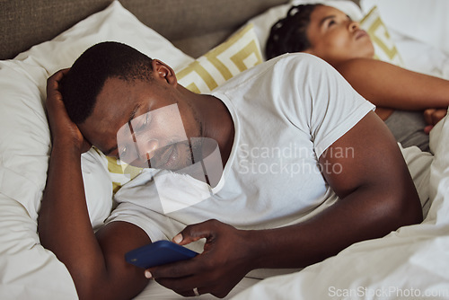 Image of Phone, addiction and bedroom with a black couple lying in bed ignoring one another in the evening. Unhappy, upset and social media with a man and woman struggling from trouble or issues in their home