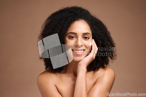 Image of Face, beauty and skincare with a model black woman in studio on a borwn background to apply lotion. Portrait, hand and hair with an attractive young female posing to promote a natural skin product