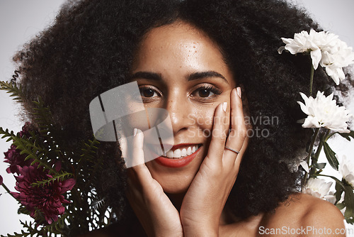 Image of Portrait, beauty and flowers with a model black woman in studio on a gray background touching her face. Skincare, plant and cosmetics with an attractive young female posing to promote natural care