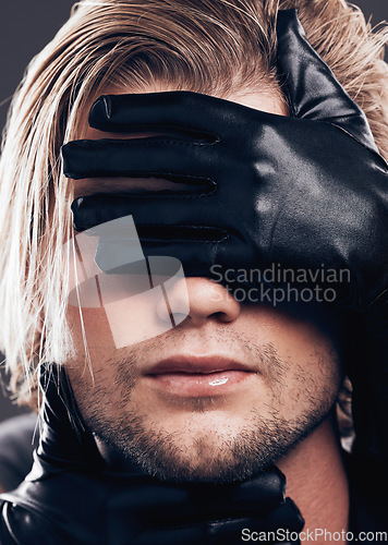 Image of Fashion, beauty and model with leather gloves on his face in a studio with edgy, punk and trendy style. Non binary, LGBTQ and closeup of a man with a luxury, fancy or stylish dark aesthetic.