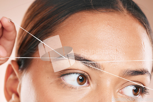 Image of Threading, eyebrows and beauty with a model black woman in studio on a beige background for hair removal. Eyes, zoom and wellness with an attractive young female using a product on her face