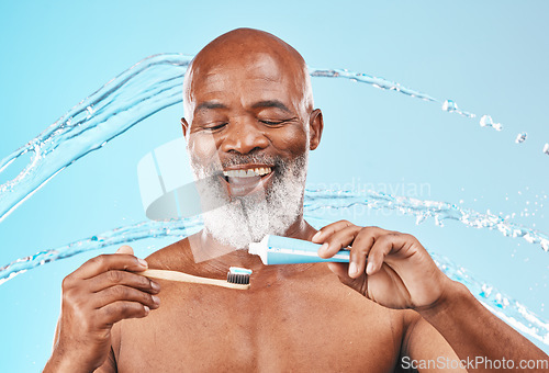 Image of Face, water splash and black man with toothbrush and toothpaste in studio isolated on blue background. Dental, oral hygiene and senior male model with product for brushing teeth, cleaning and health.