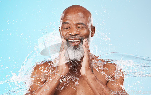 Image of Face, water and cleaning of happy black man on blue background for wellness, cosmetics and shower. Studio male model, smile and water splash in bathroom for facial health, aesthetic skincare and spa