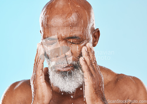 Image of Black man, face and water drip in studio for cleaning cosmetics, wellness and healthy skincare on blue background. Male model, water splash and wet shower for facial beauty, aesthetic and self care