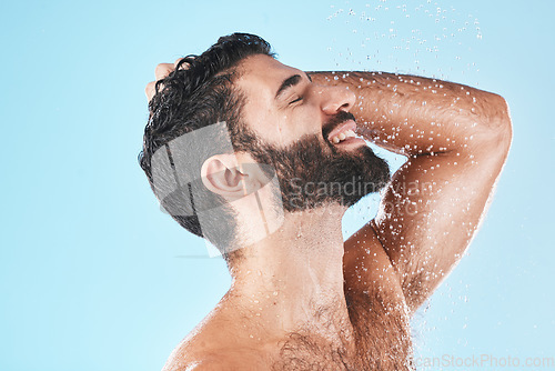 Image of Skincare, man and shower for wellness, cleaning and hygiene for routine on blue studio background. Arabic male, guy and washing for beauty, natural care and body care for grooming and water splash