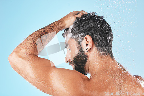 Image of Face, shampoo shower and water splash of man in studio isolated on a blue background. Water drops, hair care and back of male model washing, cleaning or bathing for healthy skin, skincare and hygiene