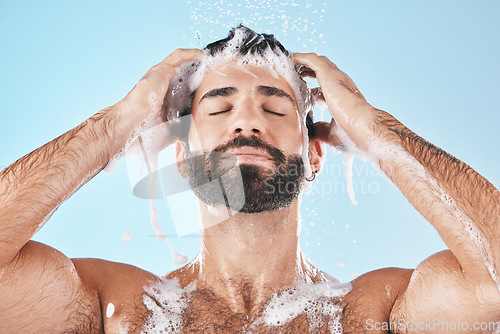 Image of Shower, man and cleaning for skincare, wellness and hygiene on blue studio background. Arabic male, guy and wash face, hair and hydration for self care, health or body care for cleanliness or routine