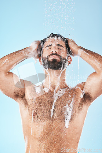 Image of Soap, water or man in shower cleaning skin, washing face or body in healthy morning grooming routine in studio. Blue background, relaxing or male model with self care, self love or foam for hair care