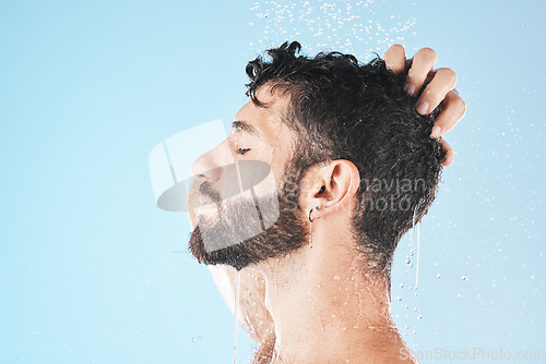 Image of Water splash, face and man in shower for skincare in studio on a blue background mock up. Dermatology, water drops and profile of male model cleaning, bathing or washing for healthy skin and hygiene.
