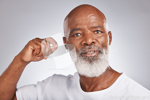 Image of Senior black man, ears cleaning and cotton bud for wax removal, grooming hygiene and self care cosmetics earwax cleaner in white studio background. Elderly african model, face and body care cleansing