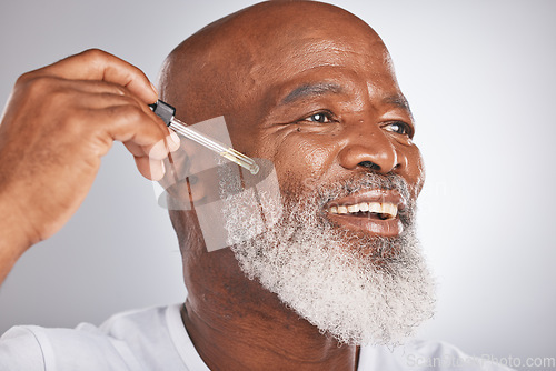 Image of Skincare, wellness and man with a face serum in a studio for a healthy, cosmetic and natural routine. Beauty, cosmetics and African male with a facial oil treatment isolated by a gray background.