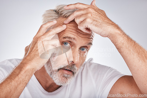 Image of Skincare, health and man pop a pimple before a cosmetic, beauty or self care treatment in a studio. Wellness, cosmetics and senior guy doing a face routine for a blemish isolated by a gray background