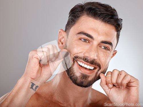 Image of Floss, teeth whitening and happy man with healthy dental lifestyle, wellness or skincare on studio background. Male model face, tooth flossing and cleaning mouth of facial smile, fresh breath or body