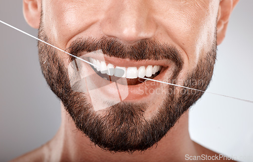 Image of Dentist, floss and mouth of man with smile on gray background in studio for wellness, healthcare and hygiene. Dental care, grooming and zoom of male model for dentistry, cleaning and flossing teeth