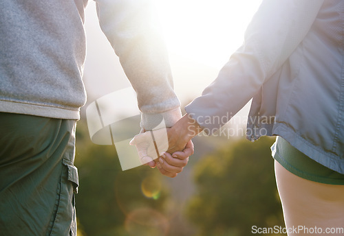 Image of Couple, holding hands with lens flare and outdoor in nature, love and bond with relationship and commitment with travel and adventure. Man, woman and hand holding, trust and support in the park.