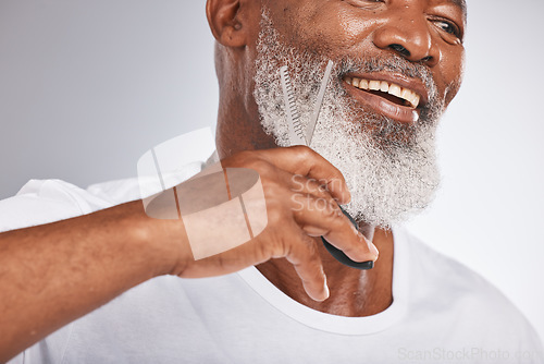 Image of Beard, beauty and shaving with a senior black man cutting his facial hair in studio on a gray background for grooming. Happy, skin and face with a mature male using scissors to cut for a shave