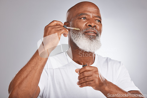 Image of Skincare, wellness and man with a face serum in a studio for a healthy, cosmetic and natural routine. Beauty, cosmetics and African male with a facial oil treatment isolated by a gray background.