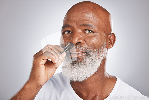 Image of Senior man, nose hair and tweezer for self care, hair removal and epilation for beauty and grooming . Headshot of black male with beard on grey studio background for body care, hygiene and clean skin