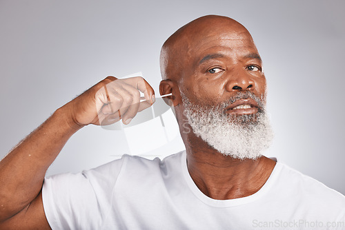 Image of Cotton swab, earwax cleaning and senior black man portrait for grooming hygiene, self care and cosmetics dirt removal in white studio background. Elderly african model, ears cleaner and body care