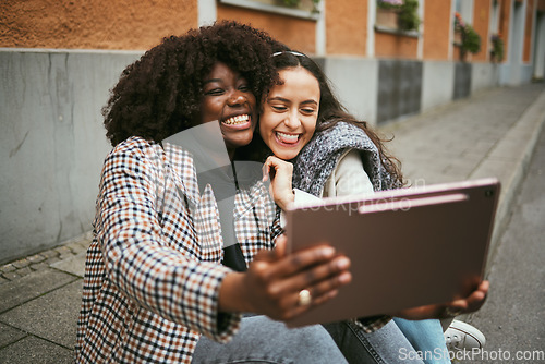 Image of City, friends and women take selfie on tablet while sitting on sidewalk laughing and happy together. Photo, video call and black woman with girl friend with urban fun and social media profile picture