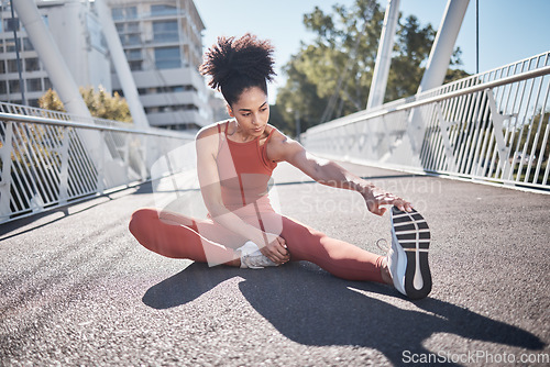 Image of Stretching legs, fitness and black woman on city bridge for exercise, running or training in sports shoes fashion. Warm up, focus and urban athlete on ground workout for body, muscle and health goals