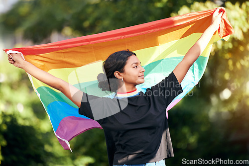 Image of Rainbow, flag and human rights with an indian woman in celebration of lgbt gay pride alone outdoor. Freedom, equality and lgbtq with a happy female outside celebrating her equality or inclusion