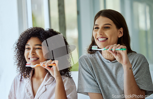 Image of Toothbrush, oral care and women friends doing a dental, health and wellness morning routine together. Happy, smile and interracial females brushing their teeth for mouth hygiene in the bathroom.