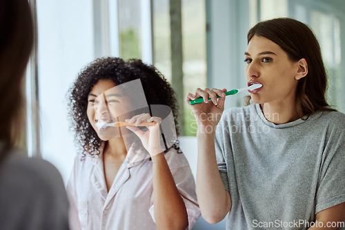 Image of Toothbrush, dental hygiene and women friends doing a self care, health and wellness routine together. Happy, smile and interracial females doing oral care while brushing teeth in the bathroom at home