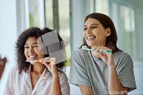 Image of Oral care, toothbrush and female friends with a hygiene, health and wellness morning routine. Happy, smile and interracial women doing a dental treatment while brushing teeth in the bathroom.