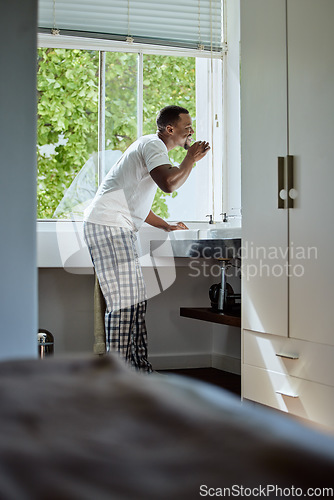 Image of Oral care, brushing teeth and black man with dental hygiene in the bathroom of his modern home. Grooming, healthcare and young African guy cleaning his mouth for a health and wellness morning routine