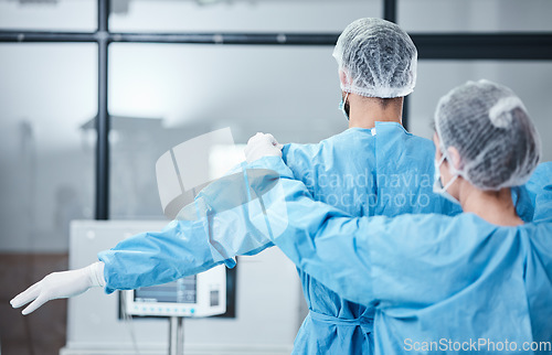 Image of Doctor, uniform and surgeon prepare for surgery, operation or medical healthcare. Nurse helping worker with safety clothing in emergency operating room, hospital and wellness support, theater or risk