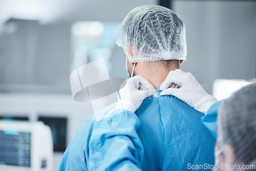 Image of Surgeon, uniform and theatre clothes for surgery, operation or medical healthcare. Nurse helping doctor with safety scrubs in emergency operating room, hospital and wellness support, medicine or risk