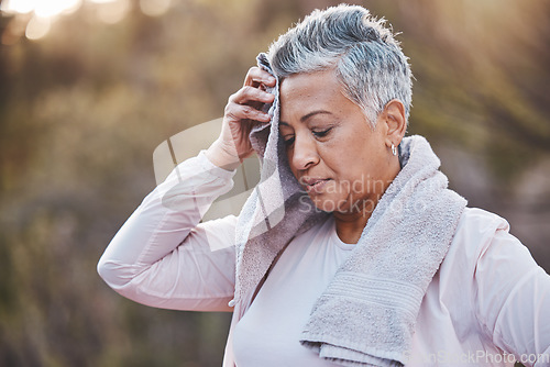 Image of Fitness, towel and tired senior woman outdoor sweating in nature after running for cardio workout, health and wellness. Elderly female wiping sweat in a forest after a run for healthy lifestyle