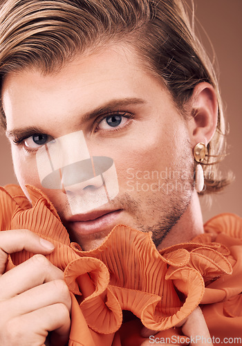 Image of Lgbtq, fashion and portrait of man with makeup, beauty and creative orange clothes on studio background. Transgender, face and queer model with skincare cosmetics, gay pride and non binary identity