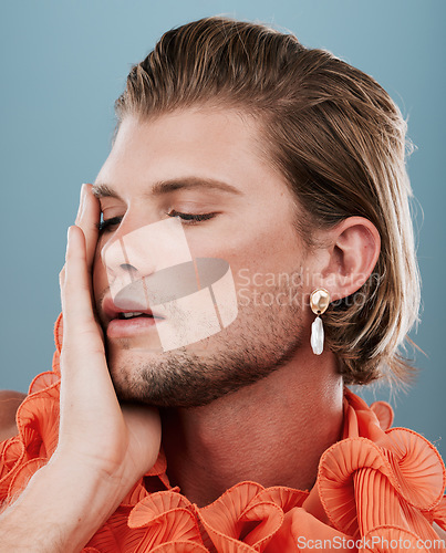 Image of LGBTQ, fashion and face of queer man with orange clothes, accessories and facial cosmetics on blue background. Transgender, gay or non binary model with beauty makeup, skincare glow or creative style