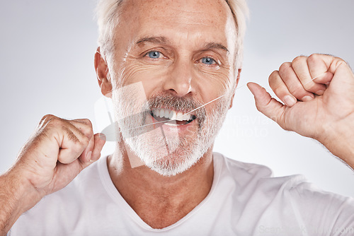 Image of Face, dental floss and senior man in studio isolated on a gray background. Portrait, cleaning and elderly male model with product flossing teeth for oral wellness, tooth care and healthy gum hygiene