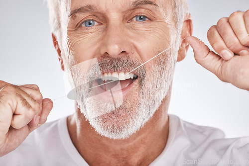 Image of Dental, floss and face of senior man in studio isolated on a gray background. Portrait, cleaning or elderly male model with product flossing teeth for oral wellness, healthy gum hygiene or tooth care