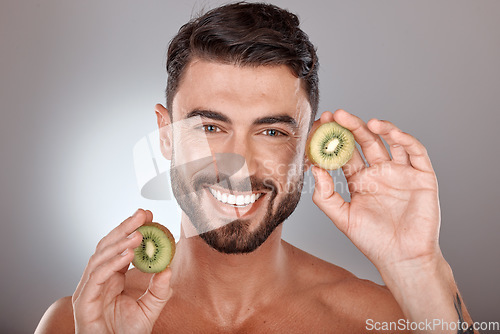 Image of Man, face and beauty with kiwi, facial care with wellness and organic treatment against studio background. Natural skincare, exotic fruit and wellness with cosmetic care and smile in portrait