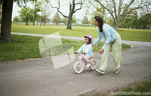 Image of Kids, bike and a mother teaching her daughter how to cycle in a park while bonding together as a family. Nature, love and children with a girl learning how to ride a bicycle with her mom outside