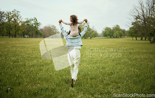 Image of Mother, child and piggyback in the nature countryside for bonding relationship, freedom or weekend travel. Mom holding daughter on back playing together for fun in the park on the open green field