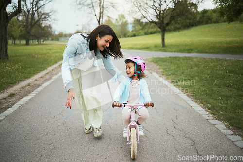 Image of Children, bike and a mother teaching her girl how to cycle in a park while bonding together as a family. Nature, love and kids with a daughter learning how to ride a bicycle with her mom outside