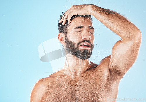 Image of Water, bathroom and a man cleaning his hair with shampoo in studio on a blue background for beauty. Hygiene, washing and a handsome male wet with droplets in the shower while bathing for haircare