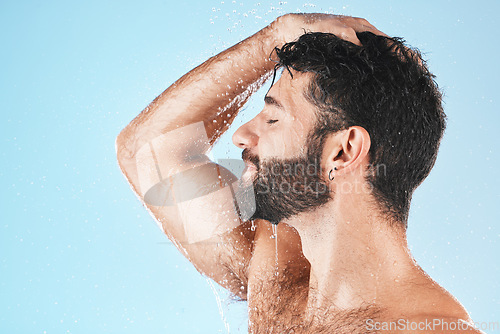 Image of Head, hair and hygiene with a model man using shampoo for cleaning in studio on a blue background. Water, wet and wellness with a handsome male washing for haircare, hydration or keratin treatment