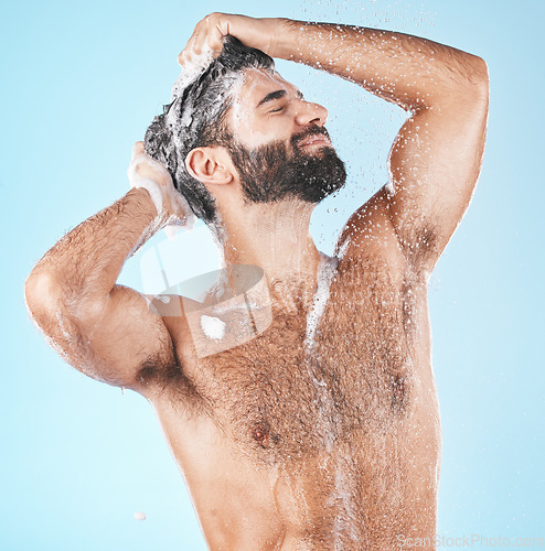 Image of Haircare, keratin and cleaning with a man in studio on a blue background to take a shower for hygiene. Water, skin and relax with a male washing his hair with shampoo treatment in the bathroom