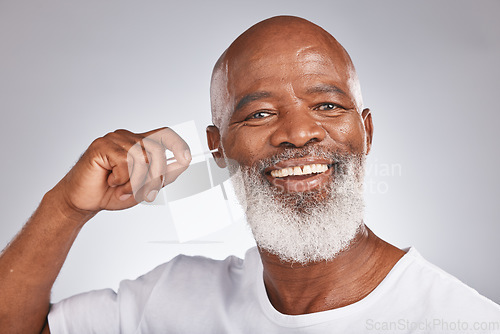 Image of Portrait, cotton and a black man cleaning his ear in studio on a gray background for hygiene or grooming. Earbud, face and smile with a happy senior male in the bathroom to clean out earwax