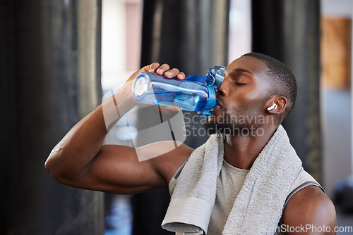 Image of Drinking water, fitness and gym with a black man athlete taking a break from his exercise or workout routine. Training, health and wellness with a sporty male having a drink for hydration or recovery